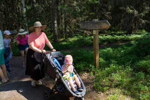 Ihmisiä kulkemassa kesäisellä polulla, joukon ensimmäisenä äiti työntää lasta rattaissa.