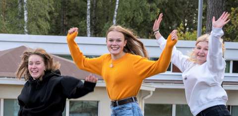 Kolme lukiolaista hyppää ilmaan. 