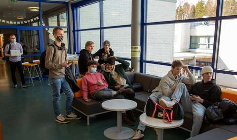 opiskelijat istuvat kilpailemassa koulun sohvilla