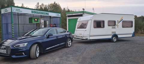 Matkailuvaunua vetävä kaasuauto biokaasuasemalla