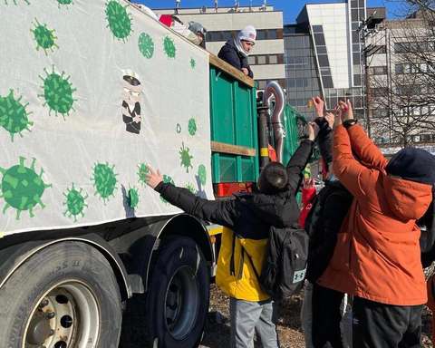 Nuoret kurottelevat karkkeja penkkarirekan vieressä, josta abit heittelevät niitä.