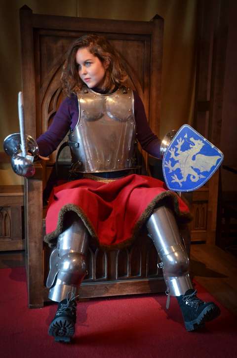 Opiskelija istuu ritariksi pukeutuneena valtaistuimella.