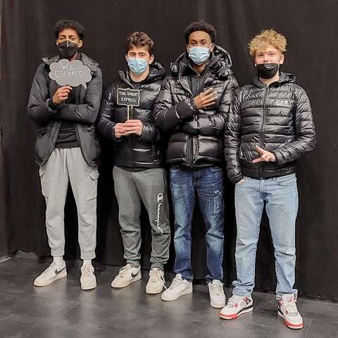 Neljä opiskelijaa pitävät kylttiä We escaped.