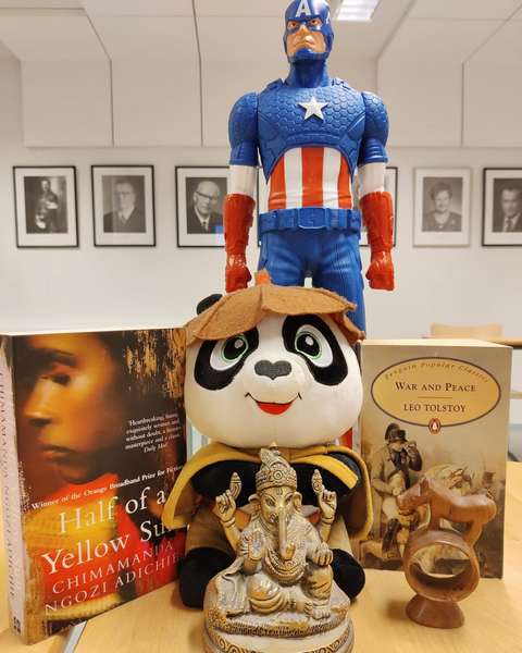 Kirjoja, hindulainen patsas, panda ja kapteeni Amerikka pöydällä.