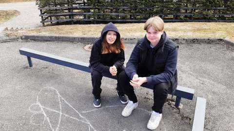 Haastateltavat oppilaat istuvat vierekkäin koulun pihalla kaiteella.