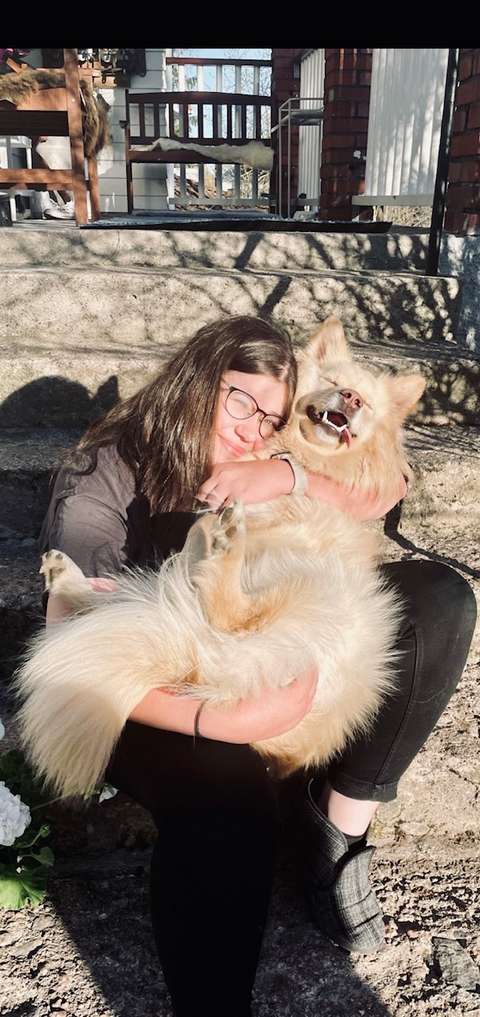 Julia paistattelee kuvassa auringossa koira sylissä. 