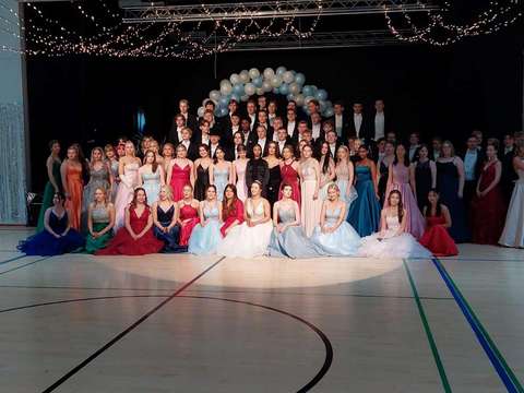 Opiskelijat perinteisessä ryhmäkuvassa lavan edessä.