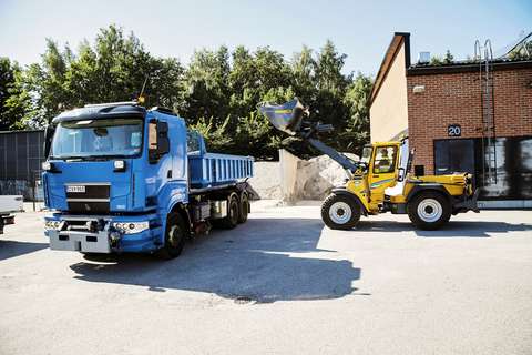 Sininen kuorma-auto ja keltainen traktori työkäytössä Espoossa