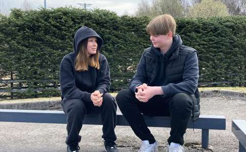 Haastateltavat oppilaat istuvat koulun pihalla vierekkäin.