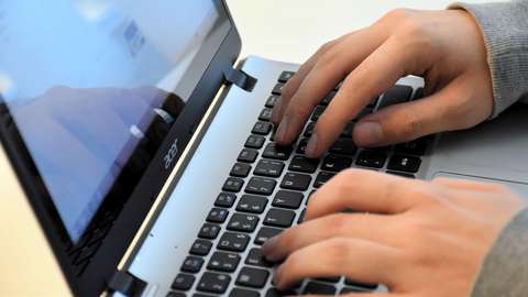 Kädet tietokoneen näppäimistöllä.