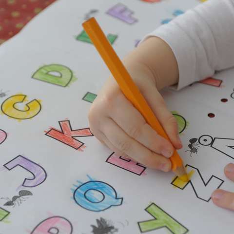 Barnet färglägger alfabetet.