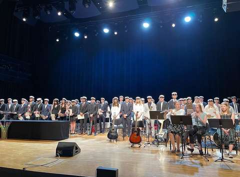 Tuoreet ylioppilaat seisovat ylioppilas-lakki päässä lavalla. 