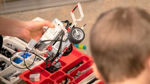 Käsi pitelee robottilegoautoa.