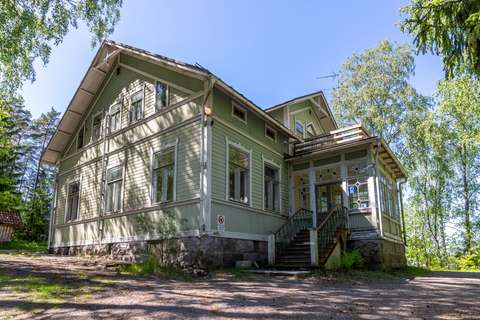 : Foto av villan Barrås. På höger sida av byggnaden finns trappor med en dörr upptill. Bakom huset finns träd.