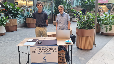 Kaksi kesäyrittäjäpoikaa seisoo myyntipöydän takana ja katsoo kameraan.