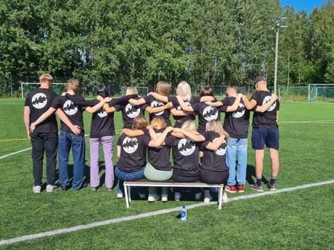 viisitoista tutoropiskelijaa seisoo selkä kuvaan päin ryhmänä