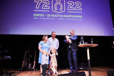 The Laukkanen family of five is on a stage receiving the The Mayor’s encouragement award. The mayor is holding a baby that received the Newcomer of the Year Award.