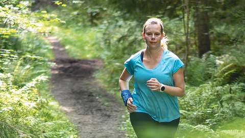 Nainen juoksee metsäpolulla