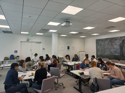 Groups of people sit around tables discussing