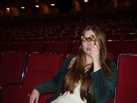 Essi istuu elokuvateatterissa kiikarit silmillä.