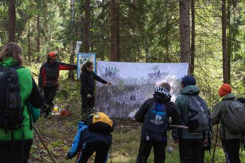 Aikuisia ja lapsia metsässä.
