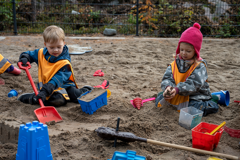 Kaksi lasta leikkii hiekkalaatikolla.
