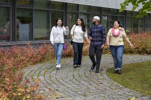 Neljä kulttuuriohjaajaa kävelee ulkona rinnakkain.