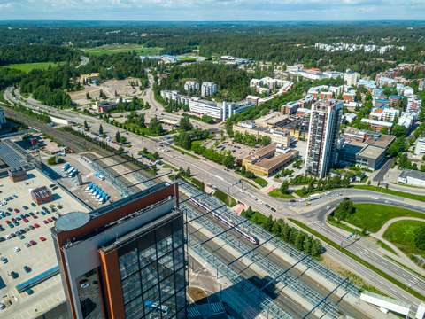Ilmakuva Leppävaaran keskustasta, jossa näkyy junaraiteet, teitä, rakennukia ja kaupunkivihreää.