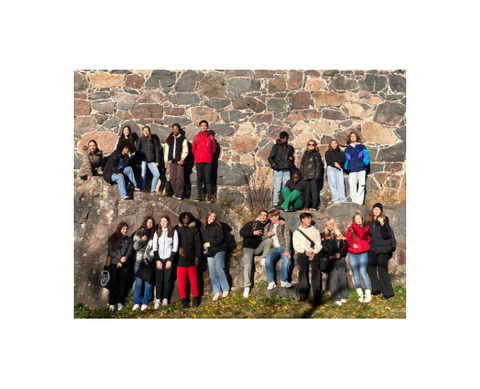 Opiskelijoita kiviseinän edessä.