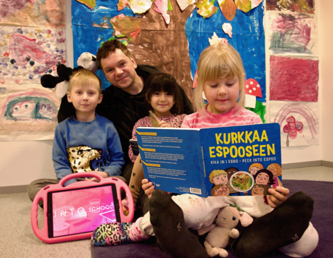 Ruusulinnan päiväkodin lapset ja muusikko Tuomas Hiedanniemi tutkivat Kurkkaa Espooseen -kirjaa.
