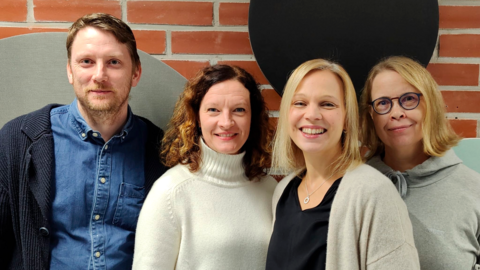 Podcast-sarjan neljännen jakson neljä keskustelijaa rivissä tiiliseinää vasten.