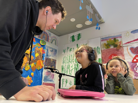 Muusikko Tuomas Hiedanniemi kuuntelee kappaletta yhdessä Ruusulinnan päiväkodin lasten kanssa.