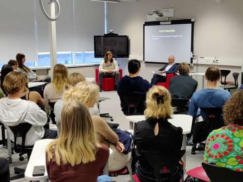Students sitting in a room listening to an interview.
