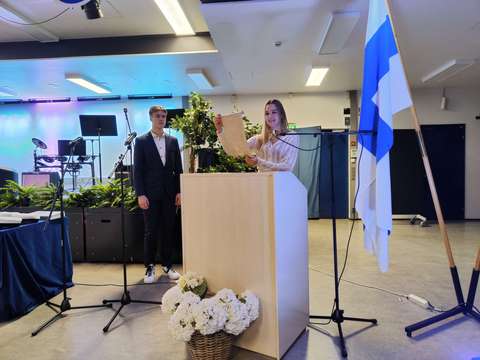 Kolmannen vuosikurssin opiskelija lukee vapauden viestin ja toisen vuosikurssin opiskelija ottaa viestikapulan vastaan.