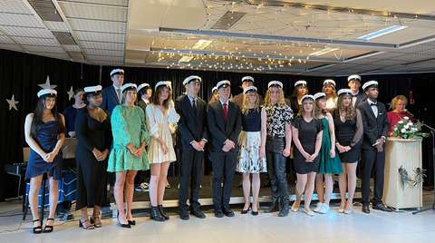 Tuoreet ylioppilaaat seisovat lavalla juhlavaatteissa ylioppilaslakki päässä. 