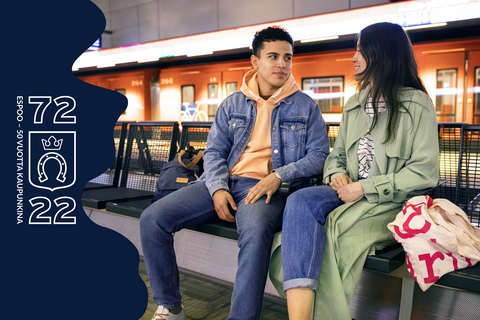 Kaksi nuorta aikuista istuu metroaseman penkillä.