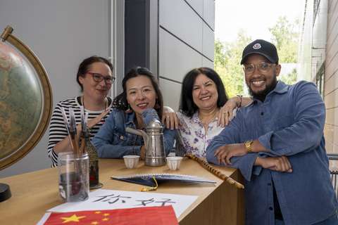 Kulttuuriohjaajat poseeraamassa kameralle. Etualalla erilaista rekvisiittaa kuten karttapallo.