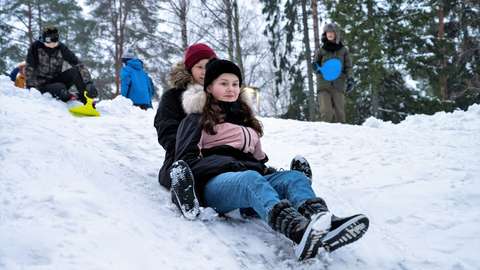 Two pupils sledding down hill.
