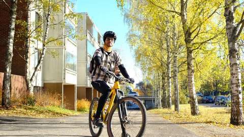 En man står på en väg med sin cykel.