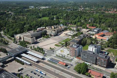 En flygbild av Esbo centrum med hus, järnvägsspår och skog.