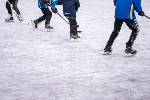 Neljä lasta pelaa jääkiekkoa tekojäällä.