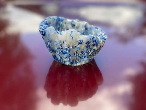 Blåvit, glänsande, tjock plastbehållare på rött underlag.