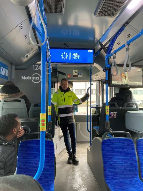 Bussissa seisoo mies, jolla on keltainen huomioliivi.