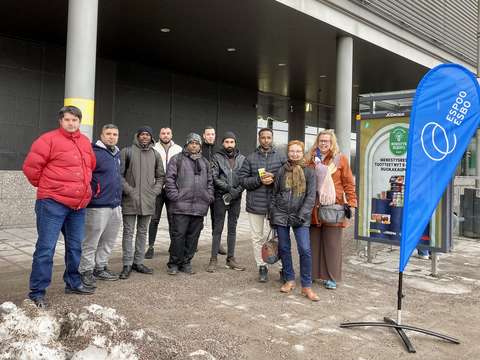 Ryhmä ihmisiä seisoo bussipysäkillä.