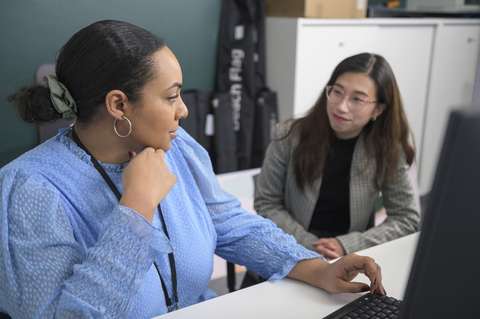 Två personer diskuterar vid en dator.