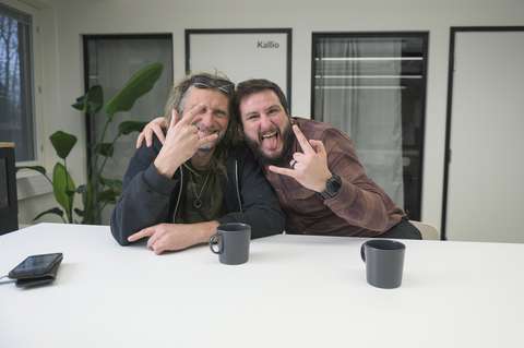 Två människor poserar tillsammans för kameran och visar rockinspirerade handgester.