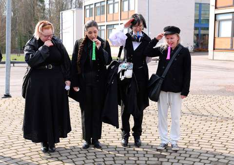 neljä opiskelijaa seisoo koulun pihalla