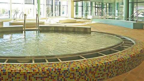 Valokuva. Kuvassa näkyy pyöreä uima-allas, jonka reunat ovat pieniä värikkäitä laattoja.