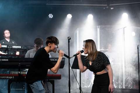 Kaksi laulajaa katsovat toisiaan esiintymislavalla.