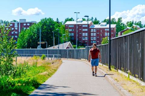  A person walking on a road next to a noise barrier.